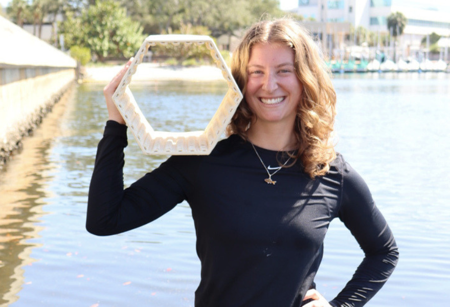 Boyer poses in the water with a 3D-printed oyster restoration brick.