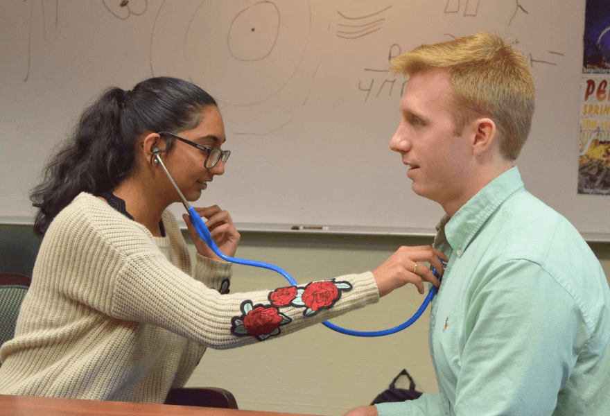Patrick Mullen teaches student how to use stethoscope in MCAT Prep course