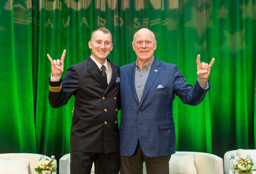 Paul Johannes holding up the "Go Bulls" sign with another man at Zita Fletcher holding 2026 Outstanding Young Alumni award ceremony