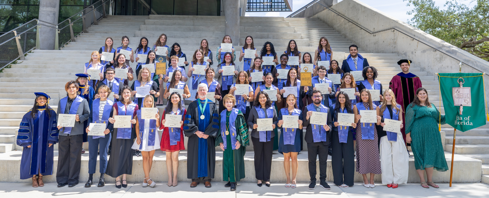 PBK 2026 initiates, faculty, and university leaders stand on Judy Genshaft Honors College amphitheater steps