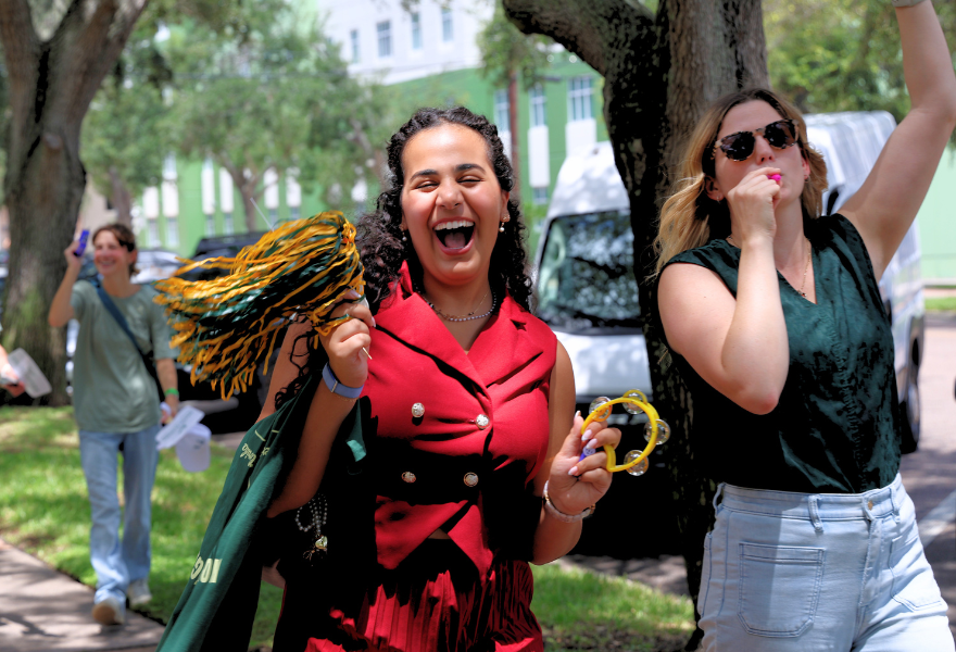 St. Petersburg student and Honors staff member process with streamers and kazoos on the sidewalk.