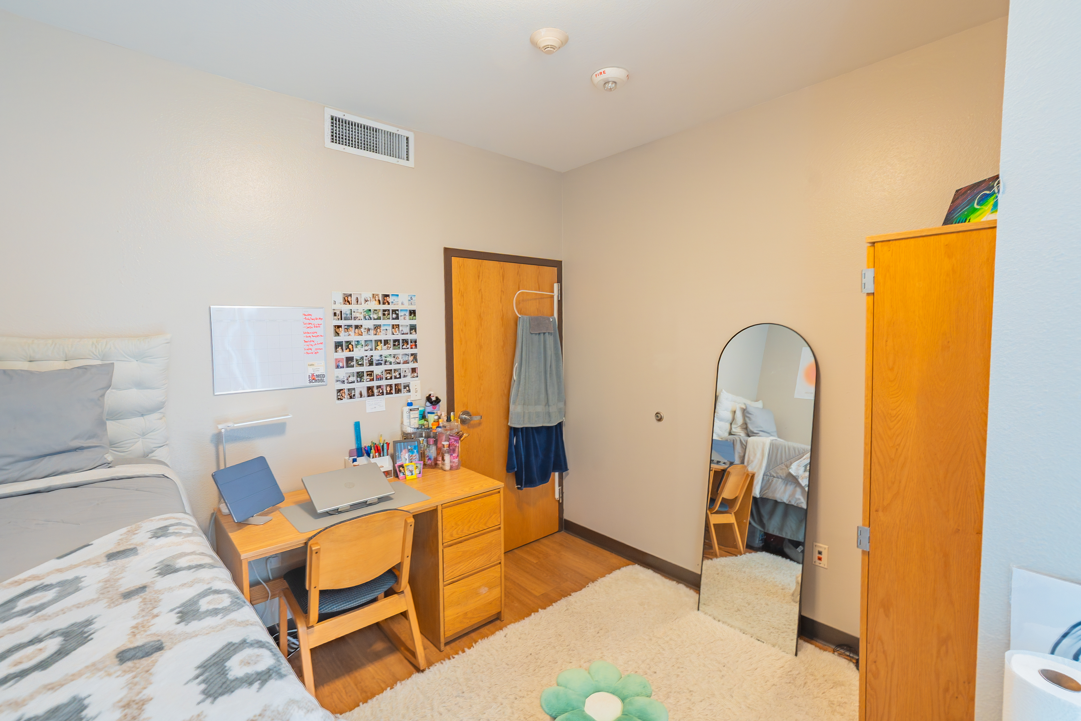Empty bedroom with a bed and two tall dressers against wall.