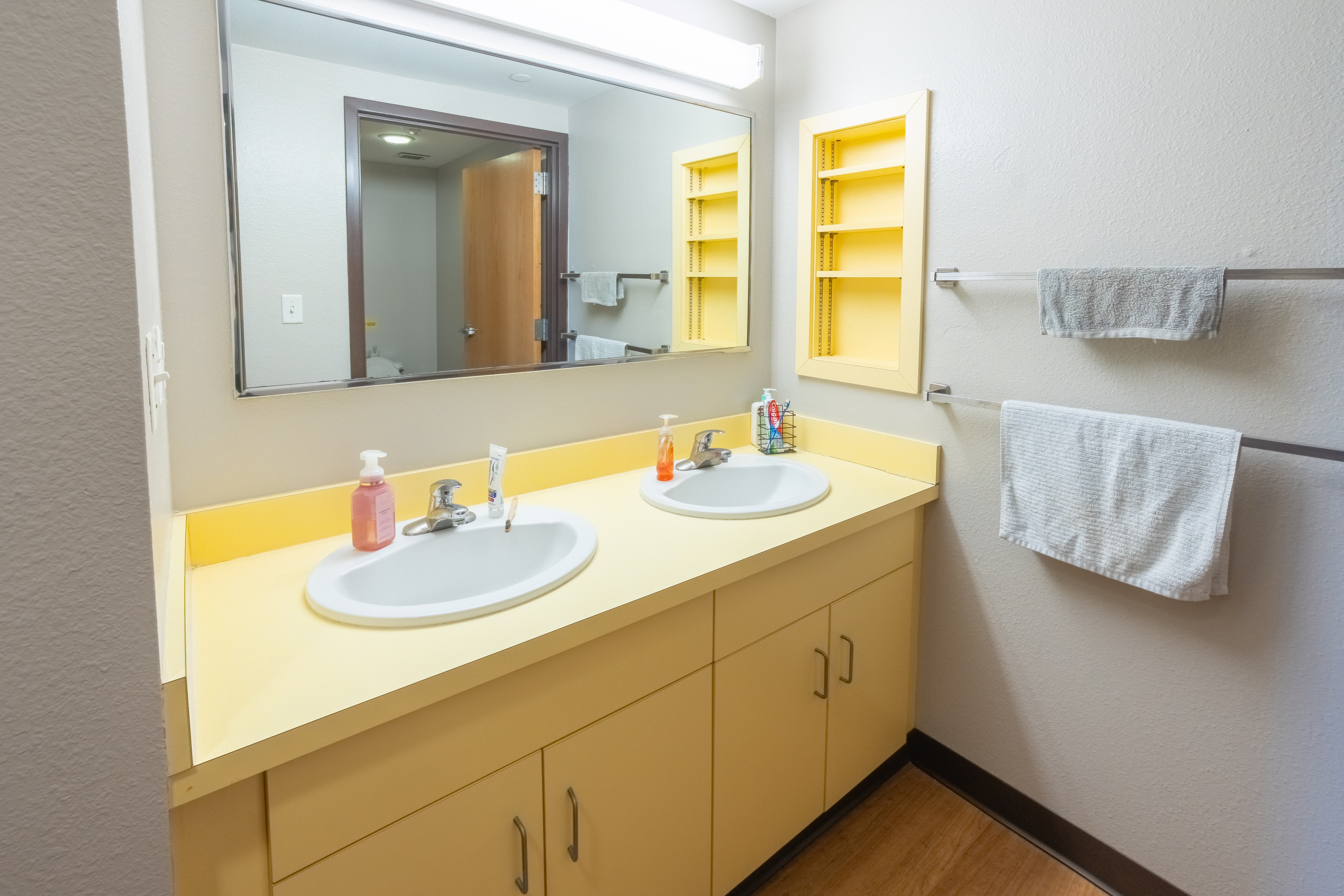 Bathroom with two yellow sinks. Large cabinet under sink and mirror above.