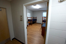 open door in hallway; can see two beds across from each other