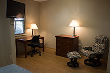 Desk with chair, dresser and reclining seat in room.