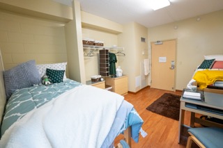 Bed in left corner with two dressers against the wall