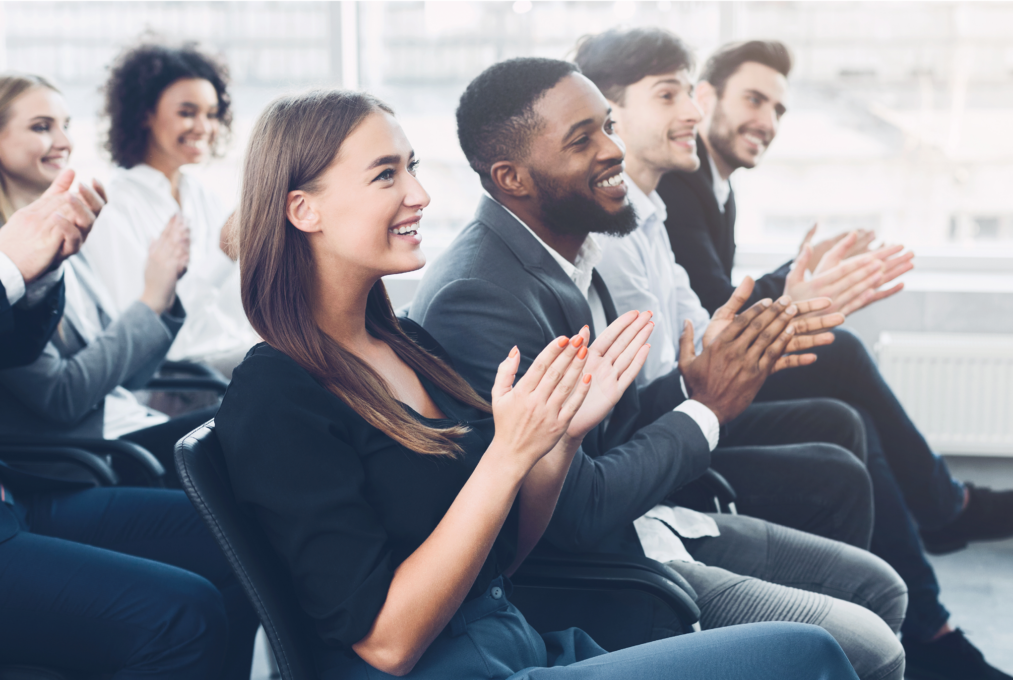 Rows of people sitting in an audience clapping. 