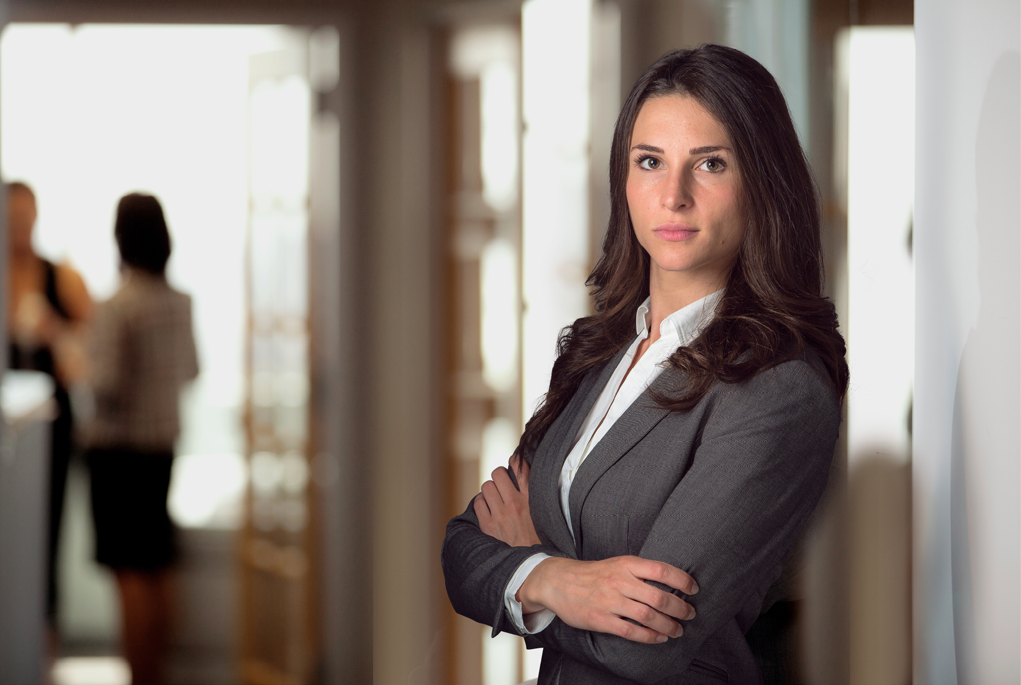 Woman posing in business attire with arms crossed. 