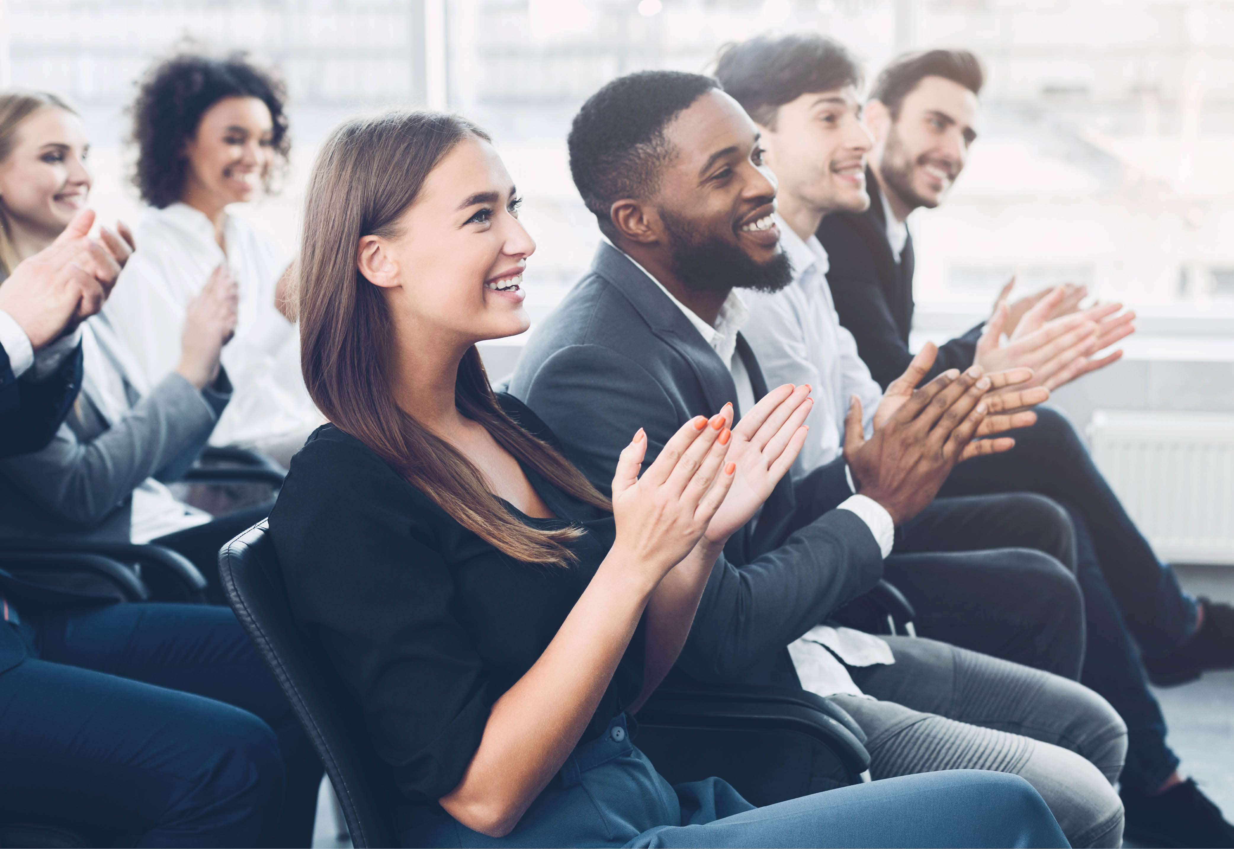 Rows of people sitting in an audience clapping. 
