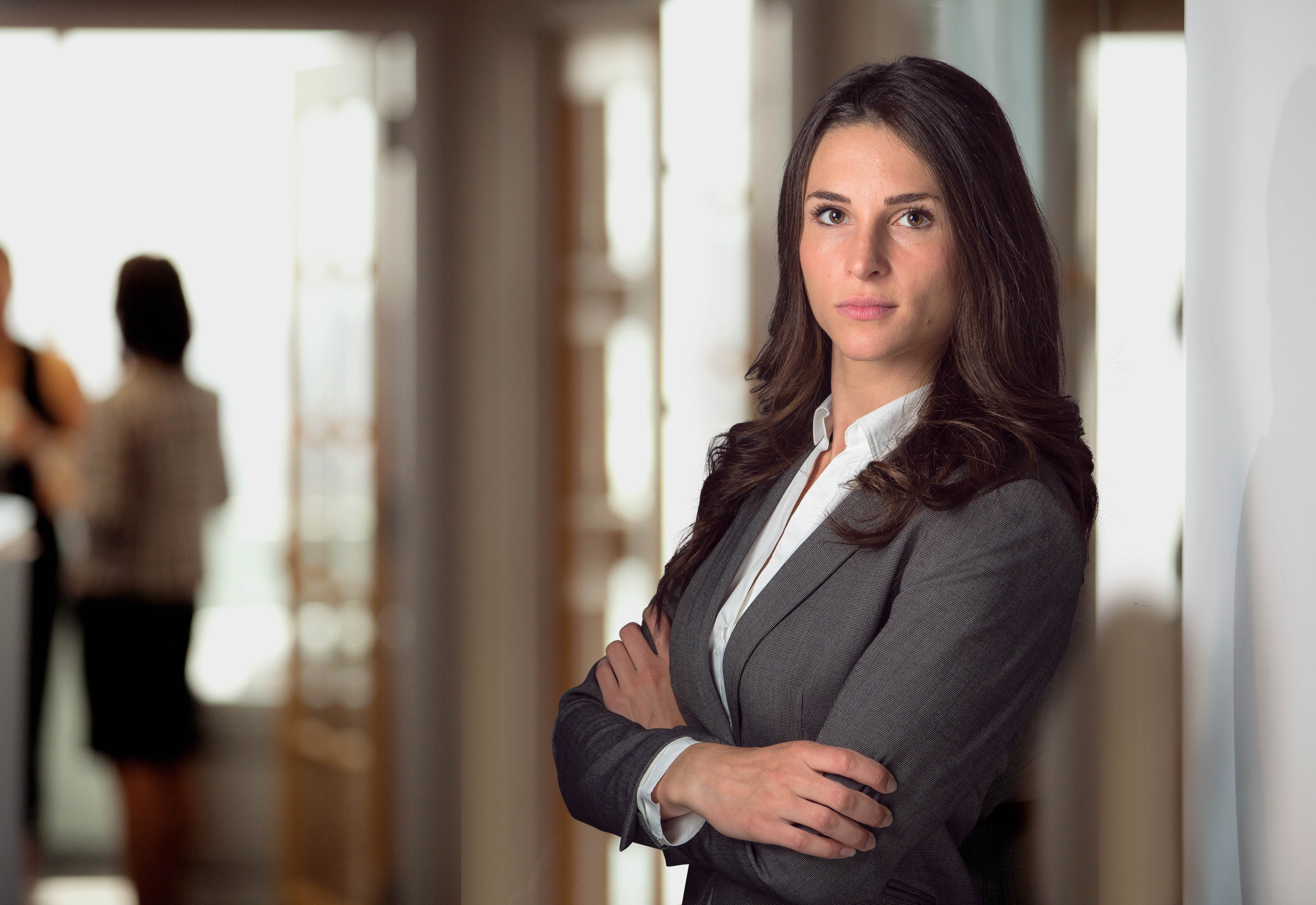 Woman posing in business attire with arms crossed. 