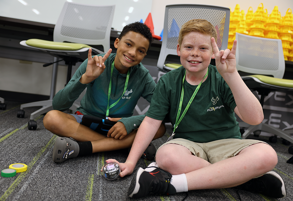 Two students hold up a USF U during everyone can code camp