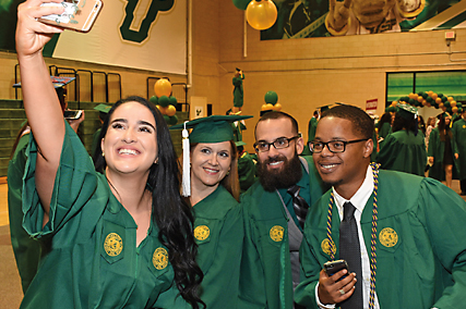 USF students at graduation in their cap and gown taking a selfie