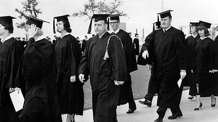 Black and white photo of charter class walking in cap and gowns