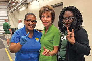 Ayesha Johnson, PhD ’16, left, and fellow volunteer Sterlyne Juste taking a picture with Judy Genshaft
