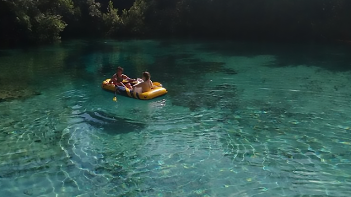 2 people floating in the water on a yellow raft