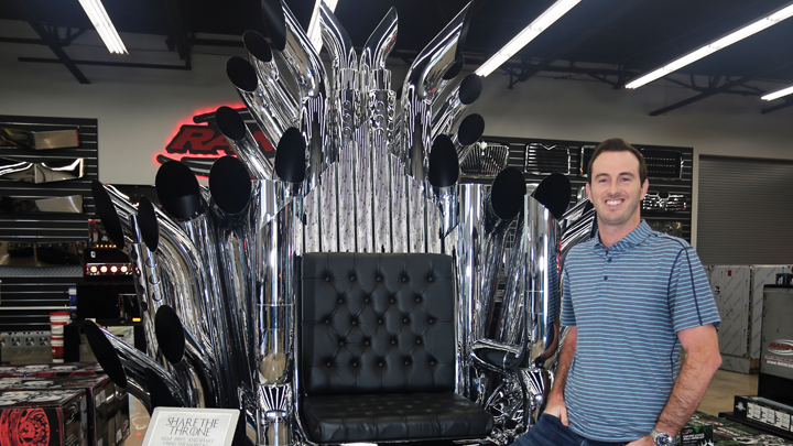 Joel Raney standing next to throne made from exhaust tips