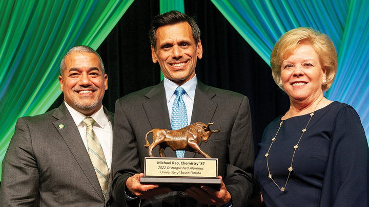 Three people posing for the camera holding a bull award