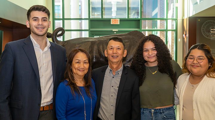 From left, Javier Perez Iglesias, Connie Leung, Tony Leung, Franjelys Reyes and Crystal pose together in front of a bronze bull statue in the Gibbons Alumni Center on the Tampa campus. 