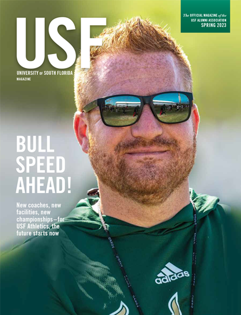Close-up of head football coach Alex Golesh, wearing USF green, with the new Porter Family Indoor Performance Facility reflected in his sunglasses.