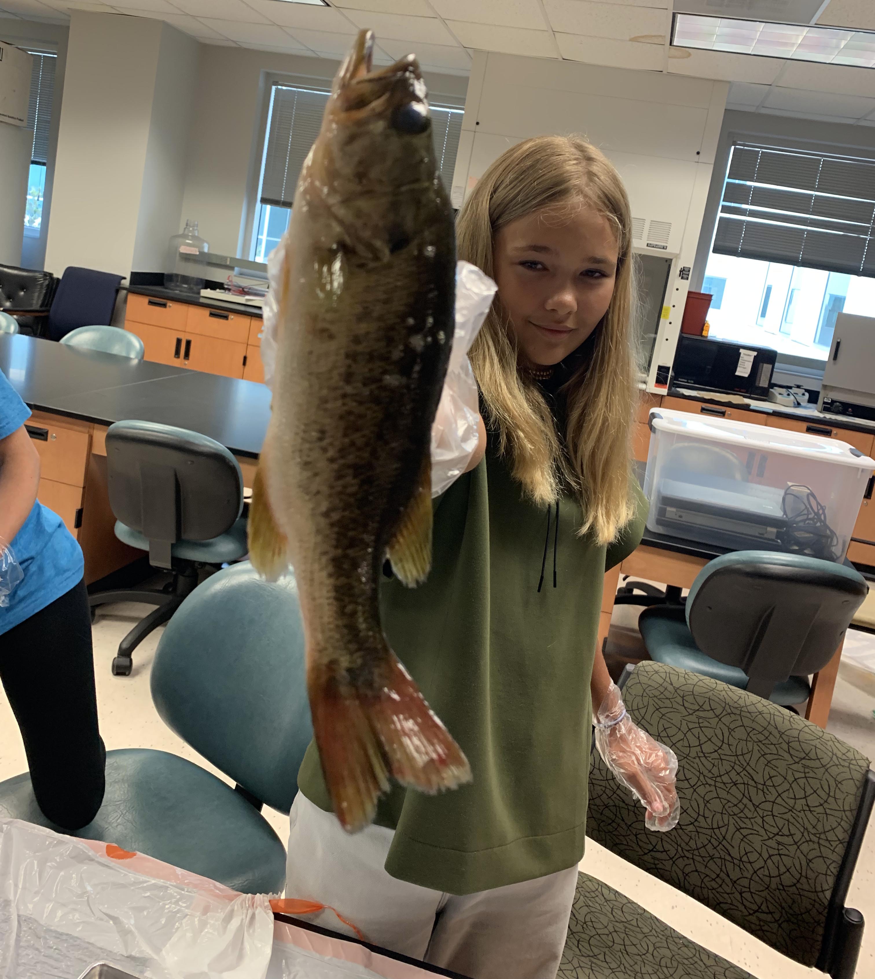 Camper Maya holding a bass to analyze its physiology.