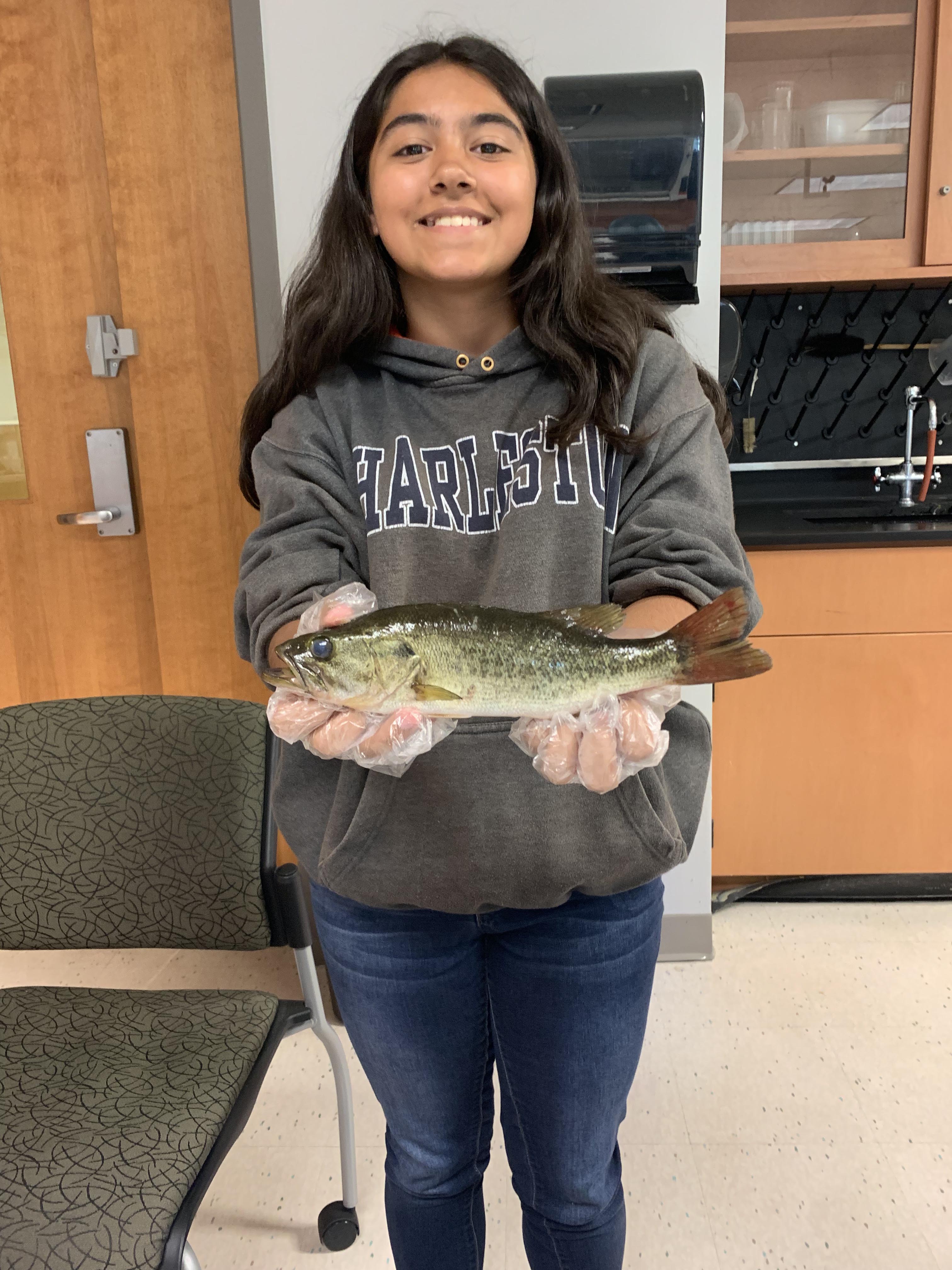 Camper Jaela holding a bass to analyze its physiology.