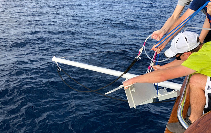 Many hands make light(er) work.  Brent Summers and others lower the heavy “Fish” over the bow of the R/V Angari.  Photo Credit: Tim Conway