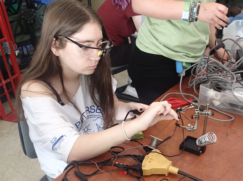 Camper Andie learns how to solder wires for the ROV lab.