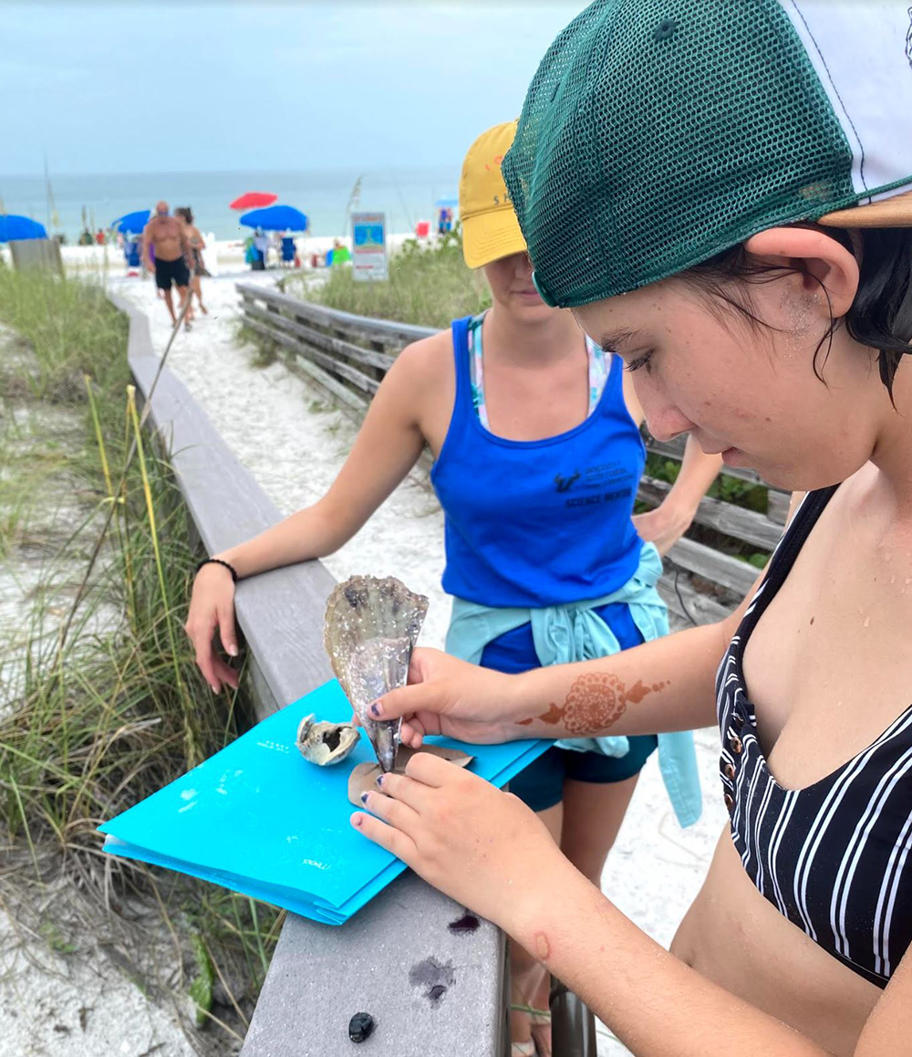 Camper Jenna uses a pen shell and ink berry juice to write on a sea grape.