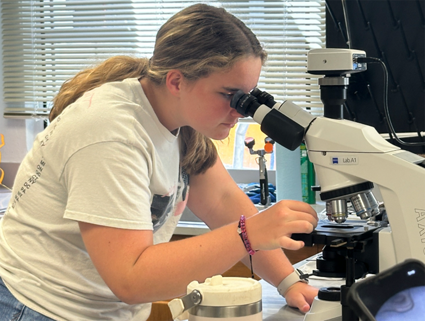 Camper Jolie looking at a sample of a fish otolith under the microscope during the toxicology lab.