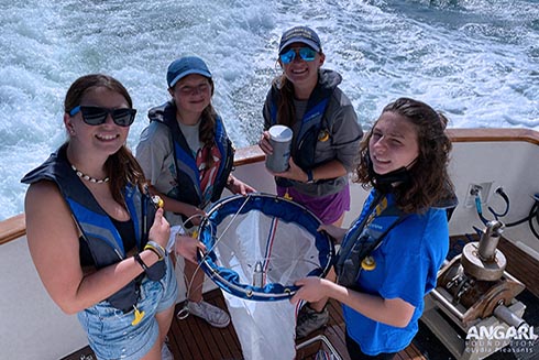 Campers Peyton, Ella, and Carissa holding the plankton net and OCG Fellow Tiff holding the plankton sample they collected. Photo credit: Lydia Pleasants, ANGARI Foundation.