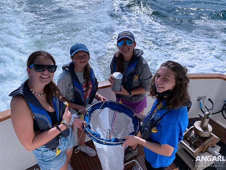 Campers Peyton, Ella, and Carissa holding the plankton net and OCG Fellow Tiff holding the plankton sample they collected. Photo credit: Lydia Pleasants, ANGARI Foundation.