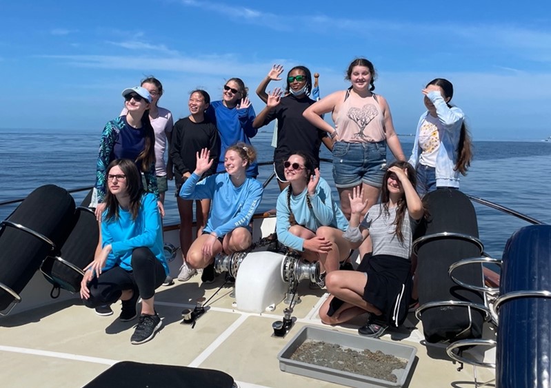 Campers smile and wave on the bow of the R/V Angari