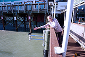 Cheryl Hapke pictured alongside the Hohonu water level sensor at Hubbard’s Marina. 