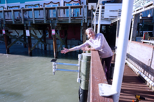 Above: Cheryl Hapke pictured alongside the Hohonu water level sensor at Hubbard’s Marina. 