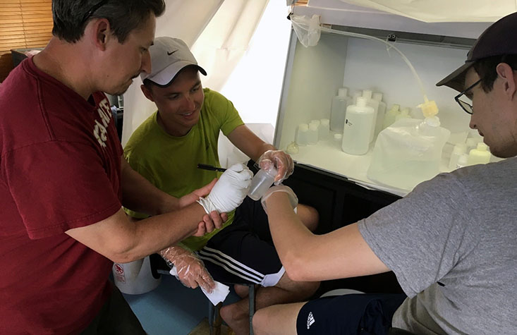 Teamwork: Dr. Peter Morton (FSU) assists Brent Summers and Travis Mellett (USFCMS) as they bag and tag another trace metals seawater sample within their “clean bubble.”