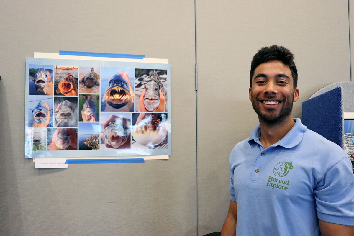 CMS grad student Keith Keel next to his collage of fish titled “Faces of Tampa Bay.” Photo Credit: Makenzie Kerr.