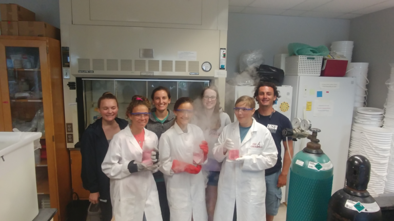 Lab rotation two group photo. Back row, left to right: Casey, Shannon, Abigail, and Juan. Front row, left to right: Delaney, Madie, and Lauren, holding acidic dry ice solutions. Photo credit: Travis Mellett.