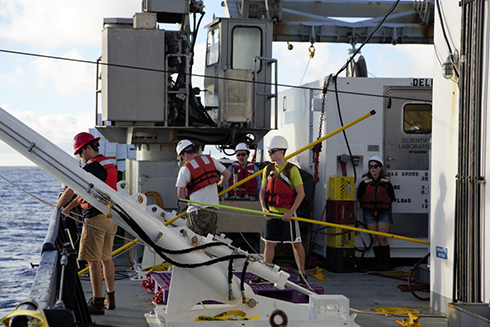 Laramie Jensen, Brent Summers and other members of the GP15 team prepare to retrieve the trace metal clean CTD rosette. Telescoping poles are used to attach tag lines. Photo Credit: Alex Fox
