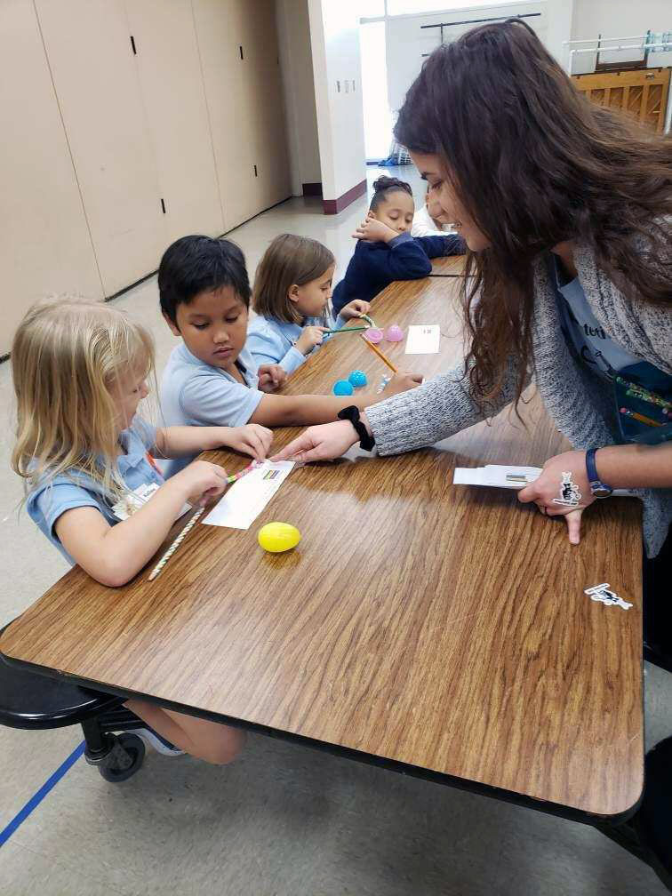 Makenzie Kerr helping the students decipher their DNA beads into DNA code.