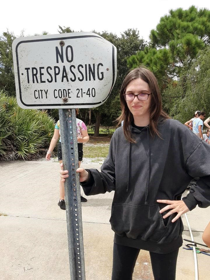 Camper Meghan posing with the floating “No Trespassing” sign found in the mangroves.