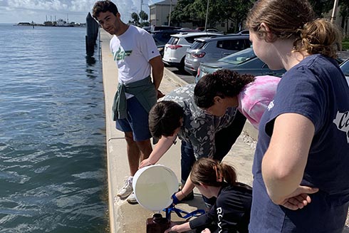 Lab leader Keith and campers Bella, Victoria, Hana and Gweni collect a water sample that contains environmental DNA.