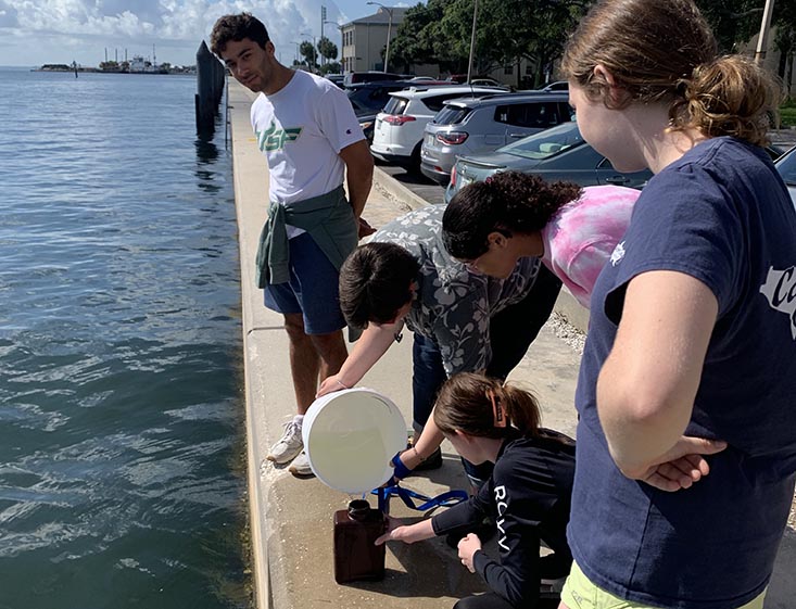 Lab leader Keith and campers Bella, Victoria, Hana and Gweni collect a water sample that contains environmental DNA.