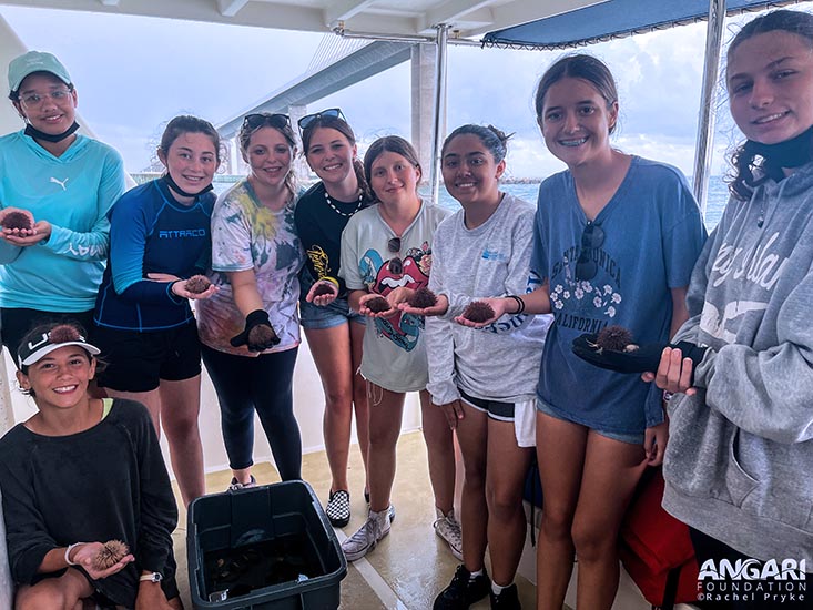 Campers Charli, Hana, Alyssa, Haleigh, Payton, Ella, Jaela, Madison, and Carissa holding sea urchins. Photo credit: Rachel Pryke, ANGARI Foundation.
