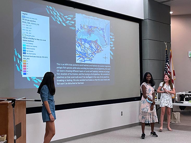 Campers Emily, Smithi, and Katie present their MPA on the final day of camp in the FWRI auditorium.
