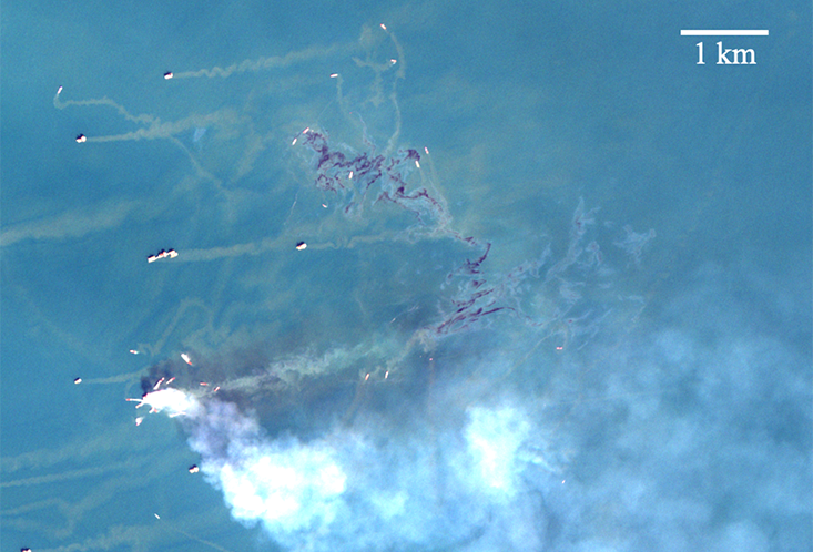 Oil spill from a fire-damaged platform, captured by the Sentinel-2 satellite of the European Space Agency. Fire smoke appears white, while oil slicks appear dark (crude and emulsified oil) or metallic color (oil sheen). Credit: Sentinel-2 data from Copernicus operated by the European Union Agency for the Space Programme in partnership with the European Space Agency. Image generated by Chuanmin Hu of University of South Florida.