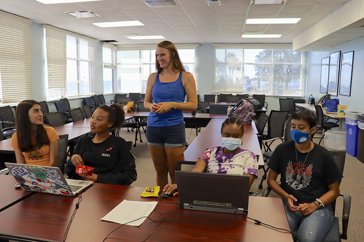 Science Mentor Becky and Peer Counselor Shiyenne assisting campers Sarah, Amiya, and Ari with creating their surplus models in Excel.