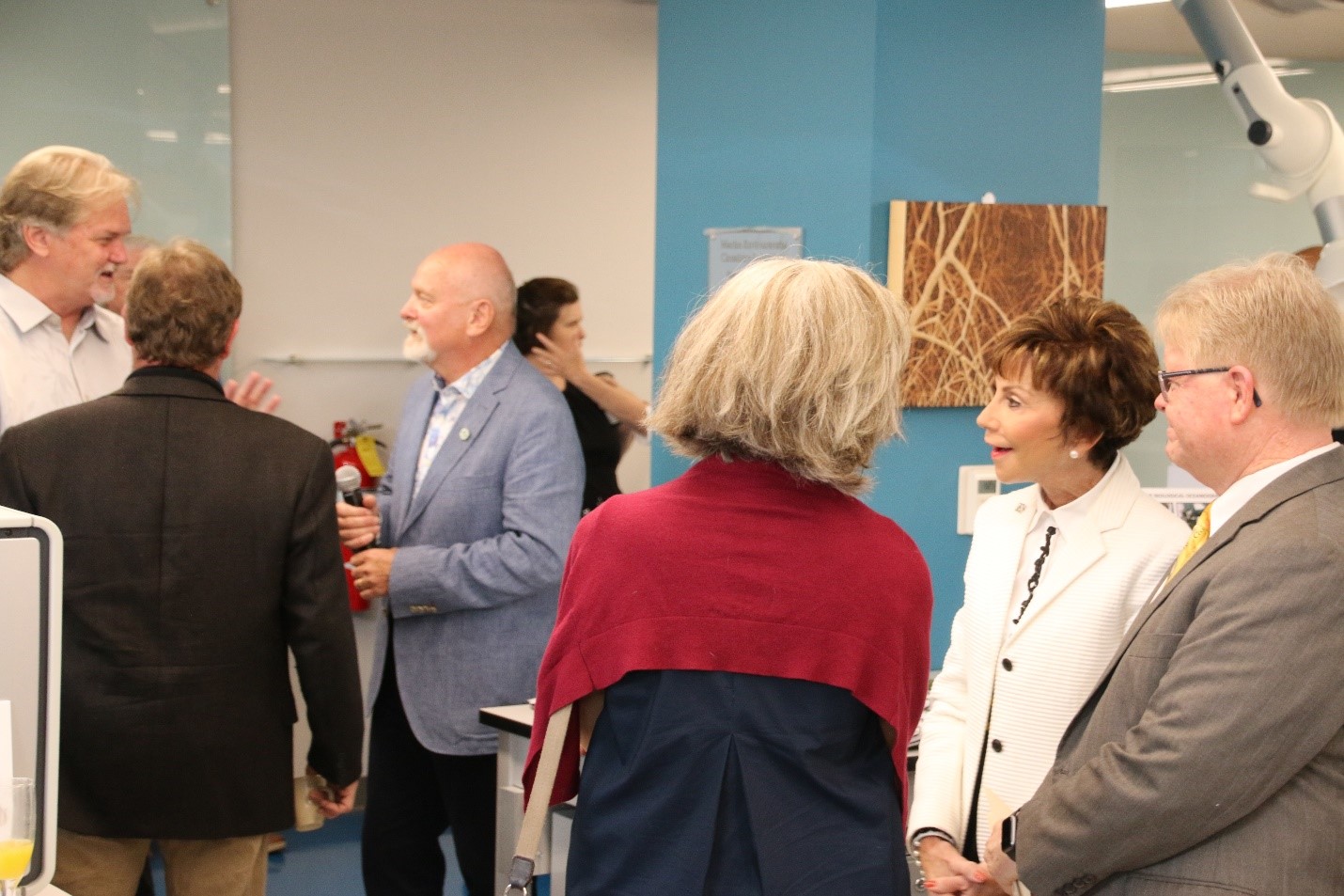 USF President Judy Genshaft (white coat, foreground) and Dr. Steve Murawski (blue coat, background) converse with other guests after giving speeches at the grand opening of the Marine Environmental Chemistry Laboratory at USF CMS. 