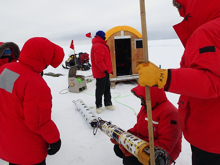 The SCINI ROV (in foreground) is being tested by a researcher prior to deployment, while the acoustic towed package is the white cylinder laying on the snow behind it. The Conestoga wagon “dry lab” is in the background. Photo credit: Stacy Kim.