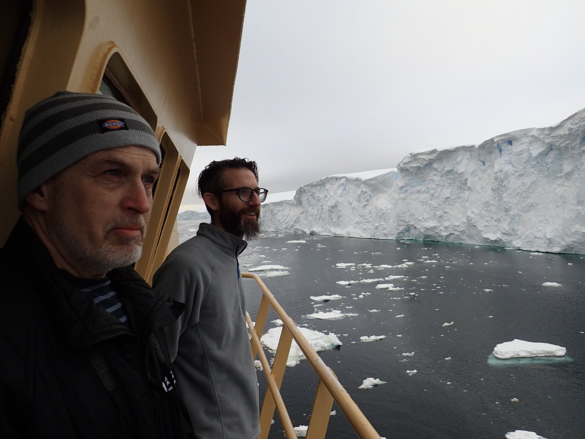 THOR scientists Alastair Graham (right) and Robert Larter (left) look on in awe at the crumbling ice face of the Thwaites Glacier margin, from the bridge deck of the R/V Nathaniel B. Palmer. (Credit: Frank Nitsche).