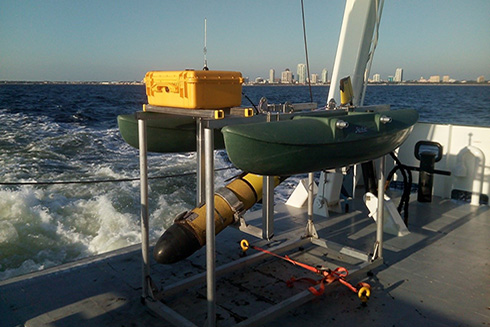 An autonomous underwater glider rests securely in its echosounder calibration float aboard the deck of the R/V Hogarth.